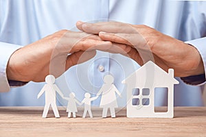 Family insurance and home. Man in shirt covers his family with his father, mother, son and daughter and the house