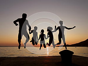 Familia saltando en el mar atardecer 
