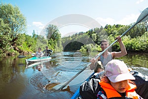 Family kayak trip. Father and daughter, and elderly couple senior and seniora rowing boat on the river, a water hike, a summer