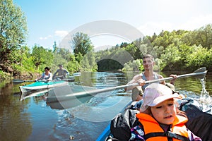 Family kayak trip. Father and daughter, and elderly couple senior and seniora rowing boat on the river, a water hike, a summer