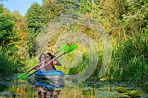 Family kayaking, mother and child paddling in kayak on river canoe tour, active autumn weekend and vacation, sport and fitness