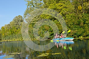 Family kayaking, mother and daughter paddling in kayak on river canoe tour having fun, active autumn weekend