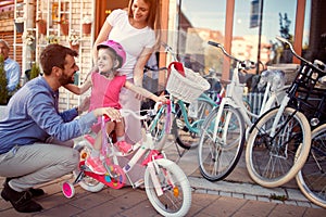 Family with kid having fun outdoor shopping new bicycle and helmets