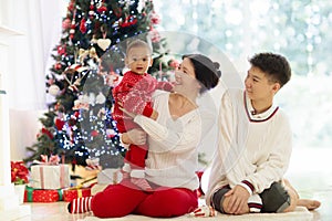 Family with kids at Christmas tree and fireplace