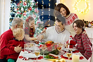 Family with kids having Christmas dinner at tree