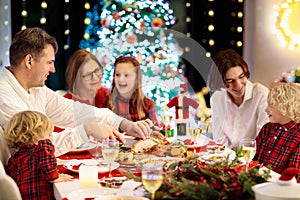 Family with kids having Christmas dinner at tree