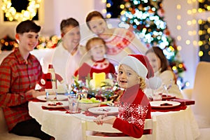 Family with kids having Christmas dinner at tree