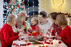 Family with kids having Christmas dinner at tree