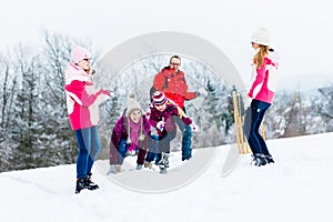 Family with kids having snowball fight in winter