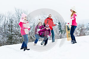 Family with kids having snowball fight in winter