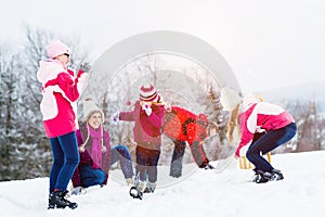 Family with kids having snowball fight in winter