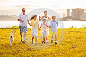 Family with kids running outdoor at sunset