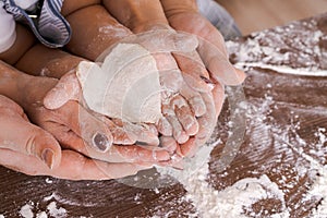 Family in kitchen, close-up palm from above lies a heart-shaped dough