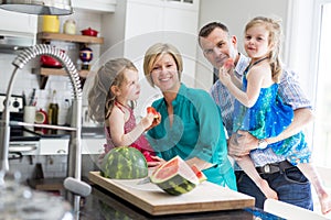 Family in the kitchen cuting the watermelon