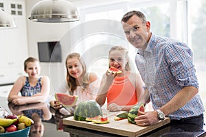 Family in the kitchen cuting the watermelon