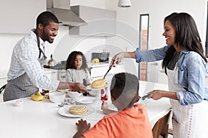 Family In Kitchen At Home Making Pancakes Together