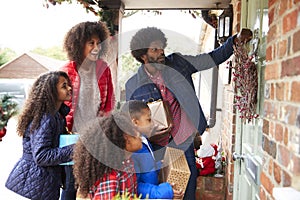 Family Knocking On Front Door As They Arrive For Visit On Christmas Day With Gifts