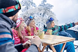 Family laughing and enjoying in hot drink at ski resort