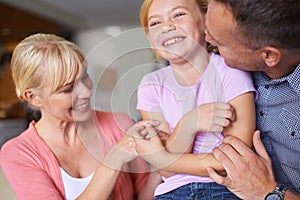 Family, laughing and parents tickling daughter in living room of home for playful bonding together. Kids, happy or love