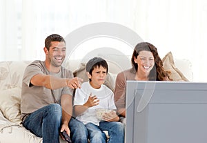 Familia sonriente mientras seguimiento televisión común 