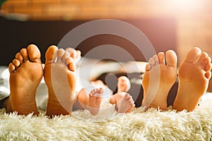 Family laying on bed, their feets on focus. Mother, father and newborn baby son