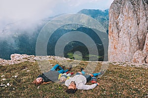 Family laying on grass in mountains mother father with child together travel hiking outdoor