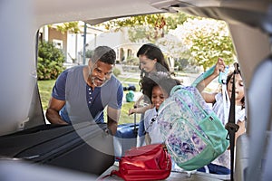 Family Leaving For Vacation Loading Luggage Into Car