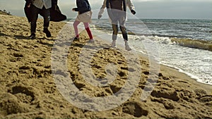 Family legs play beach together at sea shore. Fun people walking by ocean waves.