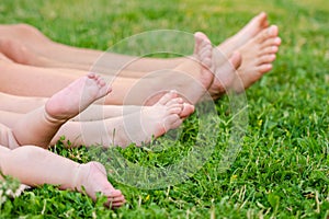 Family legs relaxing on green grass. Whole family resting