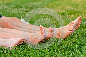 Family legs relaxing on green grass. Whole family resting