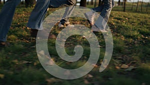 Family legs running park field golden sunlight closeup. Autumn outdoor leisure.