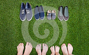 Family legs and shoes standing on green grass