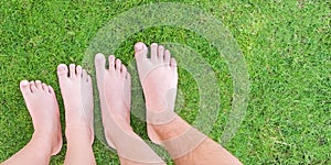 Family legs standing on green grass having fun outdoors in spring park. Close to nature, love to nature concept