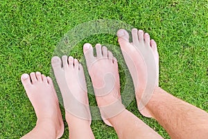 Family legs standing on green grass having fun outdoors in spring park. Close to nature, love to nature concept