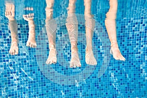 Family legs underwater in swimming pool, mother swim with children under water funny concept, sport and vacation with kids