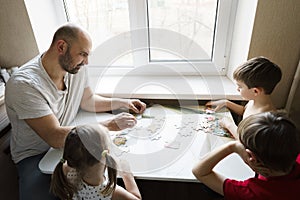 Family leisure: father, sons and daughter play board games together