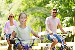 Happy family riding bicycles in summer park