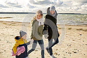 Happy family going to picnic on beach in autumn