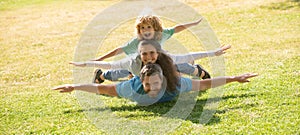 Family leisure time. Family lying on grass in park. Parents giving child piggybacks in park.