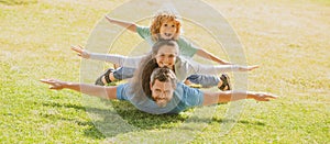 Family leisure time. Family lying on grass in park. Parents giving child piggybacks in park.