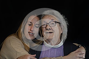 Family lifestyle portrait of elderly 80s woman hugging young grand daughter