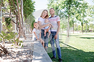 Family lifestyle portrait of a mum and dad with their children having good time in the green park