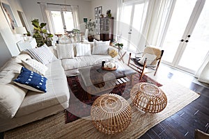 A family living room with French windows and a large comfortable corner sofa, seen in daylight, incidental people in shot