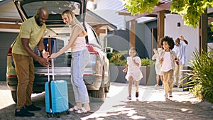 Family Loading Car And Saying Goodbye After Visit To Grandparents