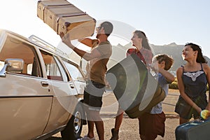 Family Loading Luggage Onto Car Roof Rack Ready For Road Trip