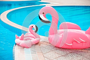 Family look. Two Pink pool floats flamingo by blue water, pool party toy. Giant Inflatable Swimming Ring. Summer vacation holiday