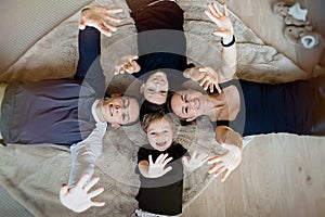 Family looking at camera and smiling while lying on the floor at home. Top view