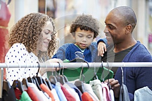 Family Looking At Clothes On Rail In Shopping Mall