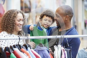 Family Looking At Clothes On Rail In Shopping Mall photo