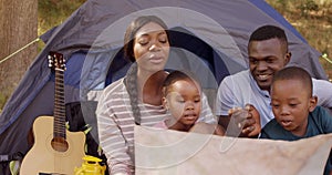 Family looking at map card in front of a tent